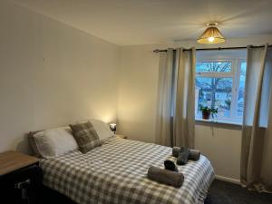 a bedroom with a bed with a checkered blanket and a window at Comfortable Home away from Home, spacious 2 bedroom town house,self catering, free parking, walking distance to Cheltenham town centre in Cheltenham