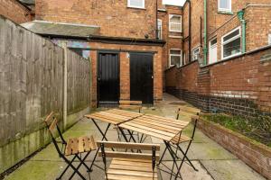 a picnic table and chairs in a courtyard with buildings at NEW DEALS - Spacious, Stylish Home - Wi-Fi, Smart TV, Parking & Outdoor Area in Leicester