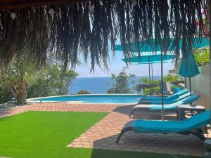 a pool with chairs and umbrellas and the ocean at Casa Sofie Salchi-Tahueca in Cuatunalco
