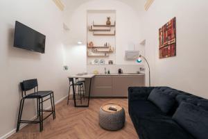 a living room with a black couch and a kitchen at Elegant design apartment in historical city center in Catania