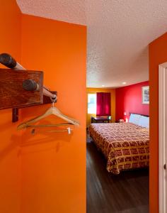 a hotel room with a bed and orange walls at Razorback Inn in Rogers