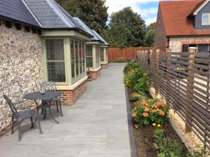 a patio with a table and chairs and a fence at Blundens Holiday Lets - Ffos Las in Chichester