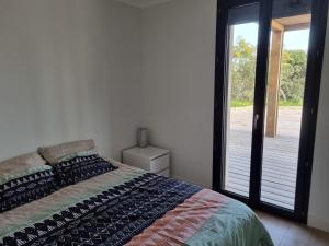 een slaapkamer met een bed en een glazen schuifdeur bij Bel appartement avec piscine privative à 150m de la plage 6 couchages in Le Barcarès
