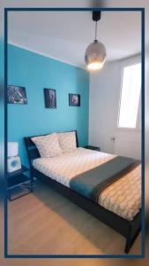 - une chambre dotée d'un lit avec un mur bleu dans l'établissement Logement 6 pers. Tout équipé, à Montluçon