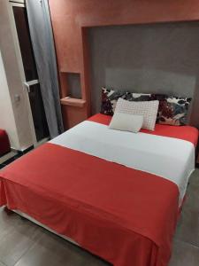 Schlafzimmer mit einem großen Bett mit roter und weißer Bettwäsche in der Unterkunft Bel appartement de 54 M² bien meublé situé au coeur de Marrakech et à proximité de toute commodité in Marrakesch