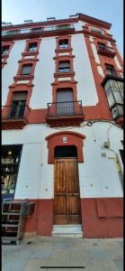 a red and white building with a wooden door at Budget & Lovely Rooms Las Setas in Seville
