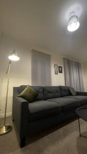 a living room with a couch and a lamp at Spacious 4 bedroom, perfect for contractors, families, private parking in Royal Wootton Bassett