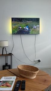 TV de pantalla plana colgada en una pared sobre una mesa en Beau T3 à 5 min du Grand Stade avec parking gratuit, en Villeneuve d'Ascq