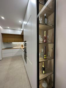 a kitchen with white cabinets and shelves with wine bottles at Sea View Apartment Luxury in Vlorë