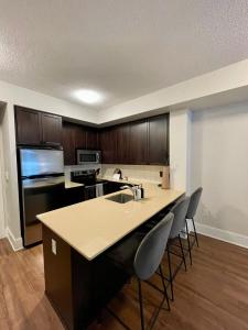 a kitchen with a sink and a counter with chairs at Cozy & charming Downtown condo! in Toronto