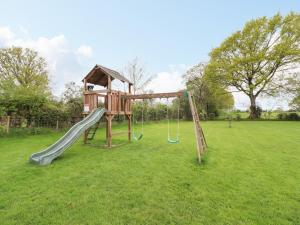 a playground with a slide in a field at Plas Cwtta in Clocaenog