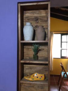 ein Holzregal mit drei Vasen und einem Kissen in der Unterkunft Prana Eco hospedaje in Cordoba