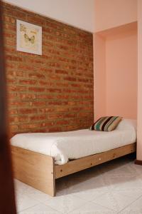 1 dormitorio con 1 cama contra una pared de ladrillo en Hotel Pintó Terraza en Esquel