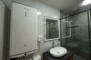 La salle de bains blanche est pourvue d'un lavabo et d'une douche. dans l'établissement Cozy Hostel, à Bishkek