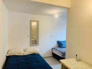 a room with a blue bed and a mirror at Apartamentos Charmosos na Avenida Principal de Buzios in Búzios