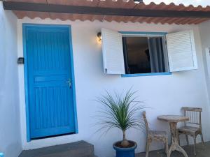 布希奧斯的住宿－Apartamentos Charmosos na Avenida Principal de Buzios，一座带蓝色门、桌子和植物的房子