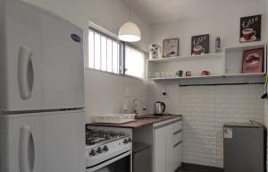 a white kitchen with a stove and a refrigerator at Casa rambla playa hermosa in Piriápolis