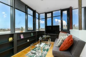 a living room with a couch and a tv and windows at Luxury Central London Penthouse in London