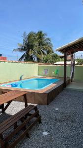 una piscina con una mesa y un banco en Casa Unamar en Cabo Frío