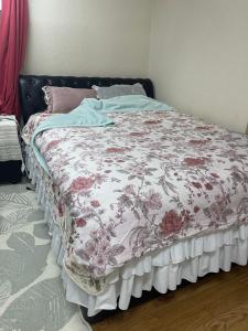 ein Bett in einem Schlafzimmer mit einer Blumendecke darauf in der Unterkunft 民泊くるり in Nagoya