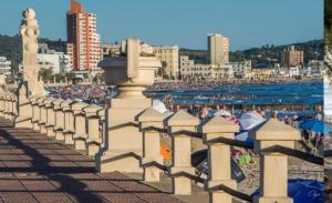 a crowd of people on a beach with umbrellas at Casa rambla playa hermosa in Piriápolis