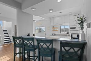 a kitchen with three bar stools and a counter at 5310 - Wright by the Beach in Kill Devil Hills