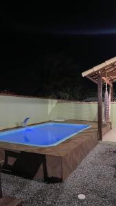 una gran piscina azul con terraza de madera por la noche en Casa Unamar en Cabo Frío