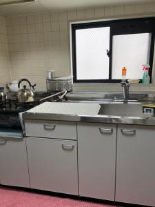 a kitchen with a sink and a stove at 民泊くるり in Nagoya
