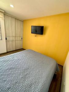 een slaapkamer met een bed en een tv aan een gele muur bij paipa casa bonita in Paipa