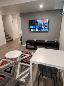 a living room with a table and a tv on a wall at A Modern & Homely 1 BR Suite in Winnipeg