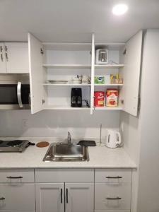 a kitchen with a sink and white cabinets at A Modern & Homely 1 BR Suite in Winnipeg
