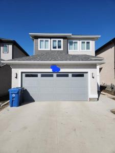 a large white house with a garage with a driveway at A Modern & Homely 1 BR Suite in Winnipeg