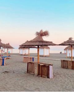 a group of straw umbrellas on a beach at SALA Apartments in Velipojë