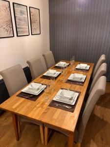 a wooden table with chairs and plates and wine glasses at Cozy 3 Bed Home in Halifax with Secure Parking - Long & short stays welcome! in Halifax