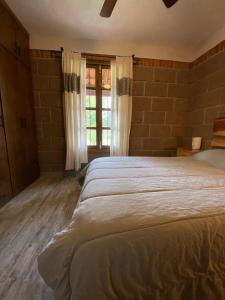 a bedroom with a large bed and a brick wall at Finca La Martina in Alcocer