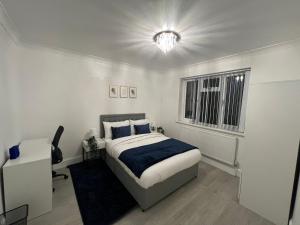 a bedroom with a bed and a desk and a window at Newly Refurbished - Affordable Four Bedroom Semi-Detached House Near Luton Airport and Luton Hospital in Luton