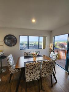 a dining room with a wooden table and chairs at Incredible Waitakere View in Auckland