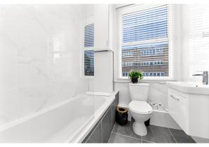 ein weißes Badezimmer mit einem WC, einer Badewanne und einem Waschbecken in der Unterkunft New and Modern flat in London! in London