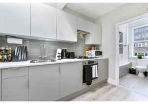 eine Küche mit weißen Schränken und einem Waschbecken in der Unterkunft New and Modern flat in London! in London