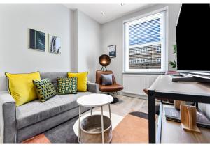 ein Wohnzimmer mit einem grauen Sofa und gelben Kissen in der Unterkunft New and Modern flat in London! in London