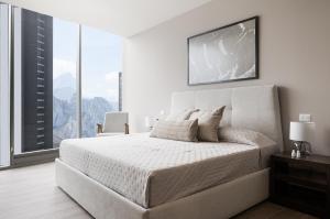 a white bedroom with a large bed and large windows at Lujo y comodidad a 2 min del consulado in Monterrey