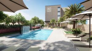 a swimming pool with chairs and umbrellas next to a building at AC Hotel by Marriott Jacksonville St Johns Town Center in Jacksonville