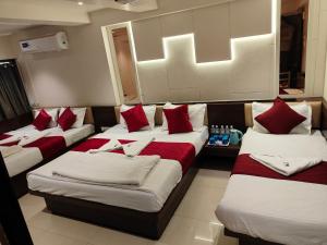 a room with four beds with red and white pillows at Hotel Anand Palace in Shirdi