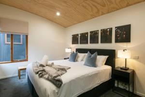 a bedroom with a bed with white sheets and blue pillows at Frueauf Village in Falls Creek