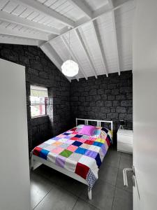 ein Schlafzimmer mit einem Bett mit einer bunten Decke in der Unterkunft Cantinho dos Cagarros in Lajes do Pico