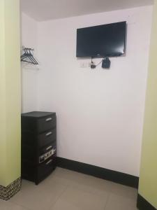 a room with a wall with a tv and a dresser at Hostal Venecia -Tu casa en Manta. in Manta