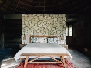 a bedroom with a bed and a stone wall at Nomade Tulum in Tulum