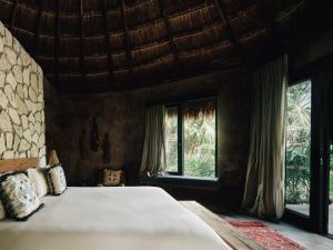 a bedroom with a large bed and windows at Nomade Tulum in Tulum