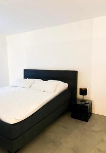 Cama en habitación con pared blanca en Suite One Einsteinstraße en Múnich