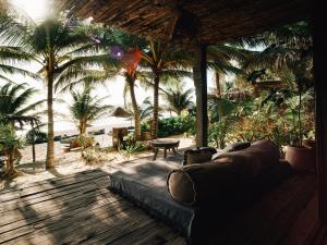 a couch in a living room with palm trees at Nomade Tulum in Tulum